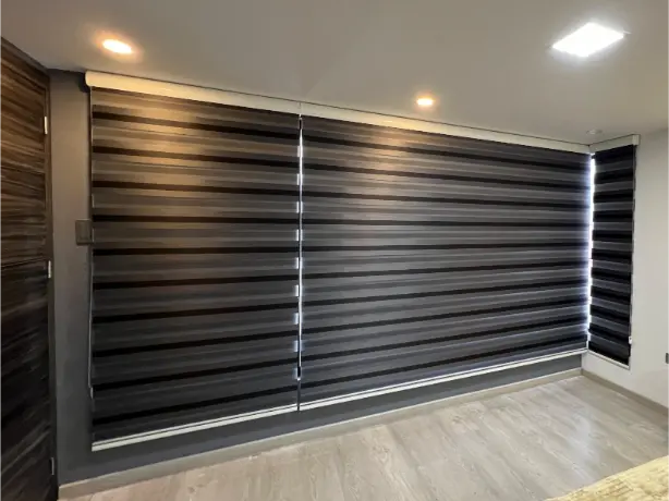 Cortina zebra plomo regulando luz nocturna en salón