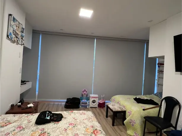 Cortina blackout blanca aislando luz cálida en dormitorio